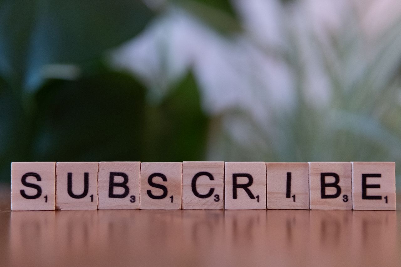 Services Close-up of the word 'SUBSCRIBE' spelled with wooden letter tiles on a table.