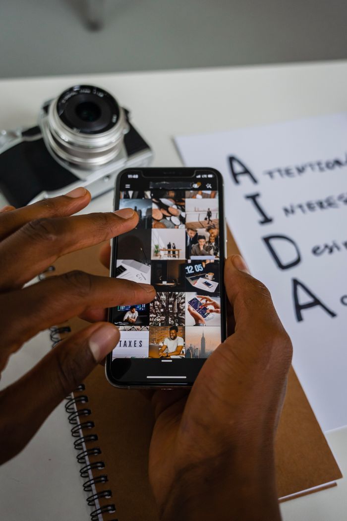 About Close-up of hands using a smartphone with a camera and notepad nearby, indoors.